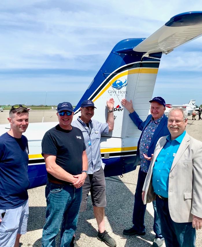 Members of the Hope Air community gather beside a Hope Air aircraft displaying the Give Hope Wings logo, an initiative that raises awareness and support for the organization’s mission. Through events, fundraising flights, and volunteer pilots across Canada, Hope Air helps patients overcome distance and financial barriers to reach essential medical care.