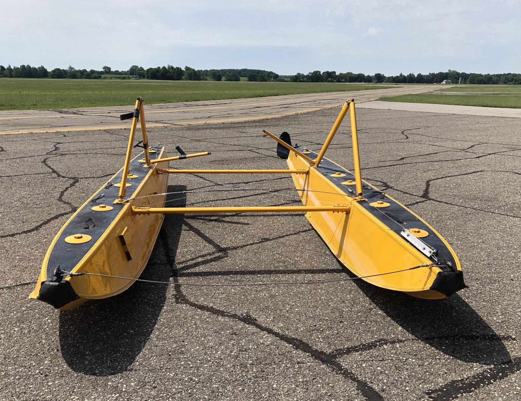Paire de flotteurs EDO 1320 jaunes avec spreader bars et struts sur un tarmac