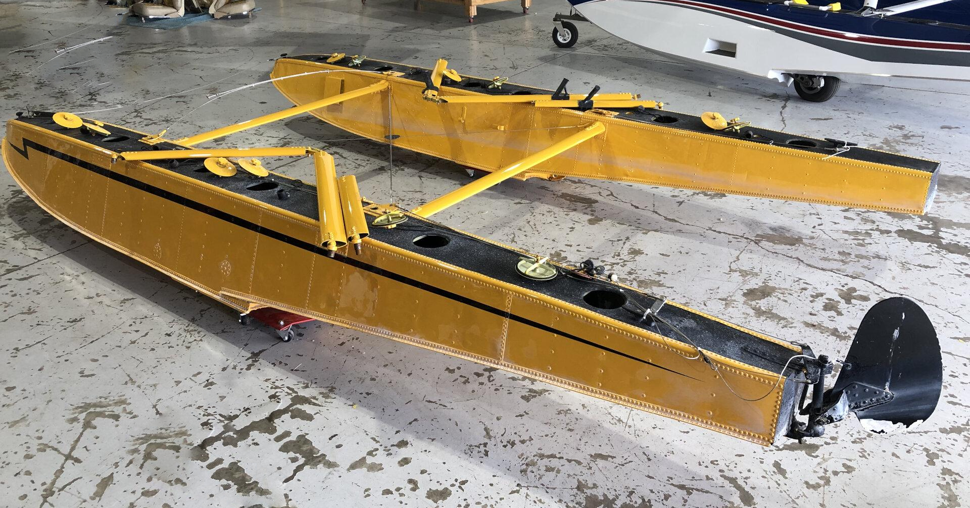 Paire de flotteurs EDO 1320 jaunes dans un hangar, avec gouvernail d’eau visible à l’arrière